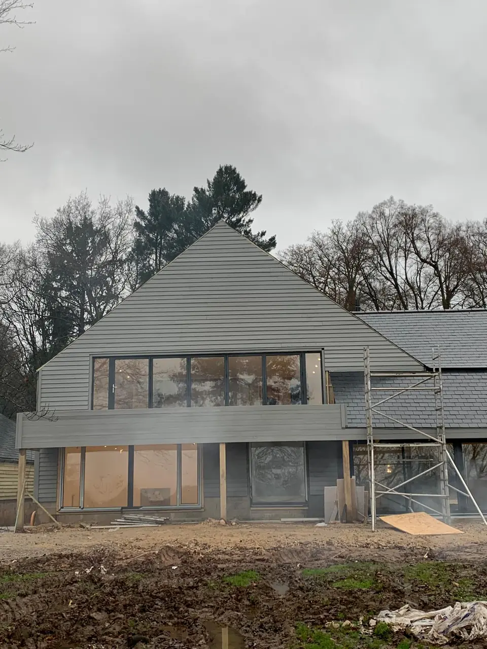 Gable end of a barn building with grey cladding going on above a long run of windows