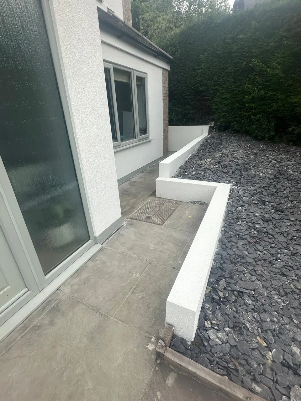 Low white rendered garden wall curving along a path beside the house